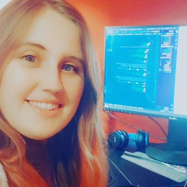 Amanda Hotchkiss smiling at the camera in front of a coding setup